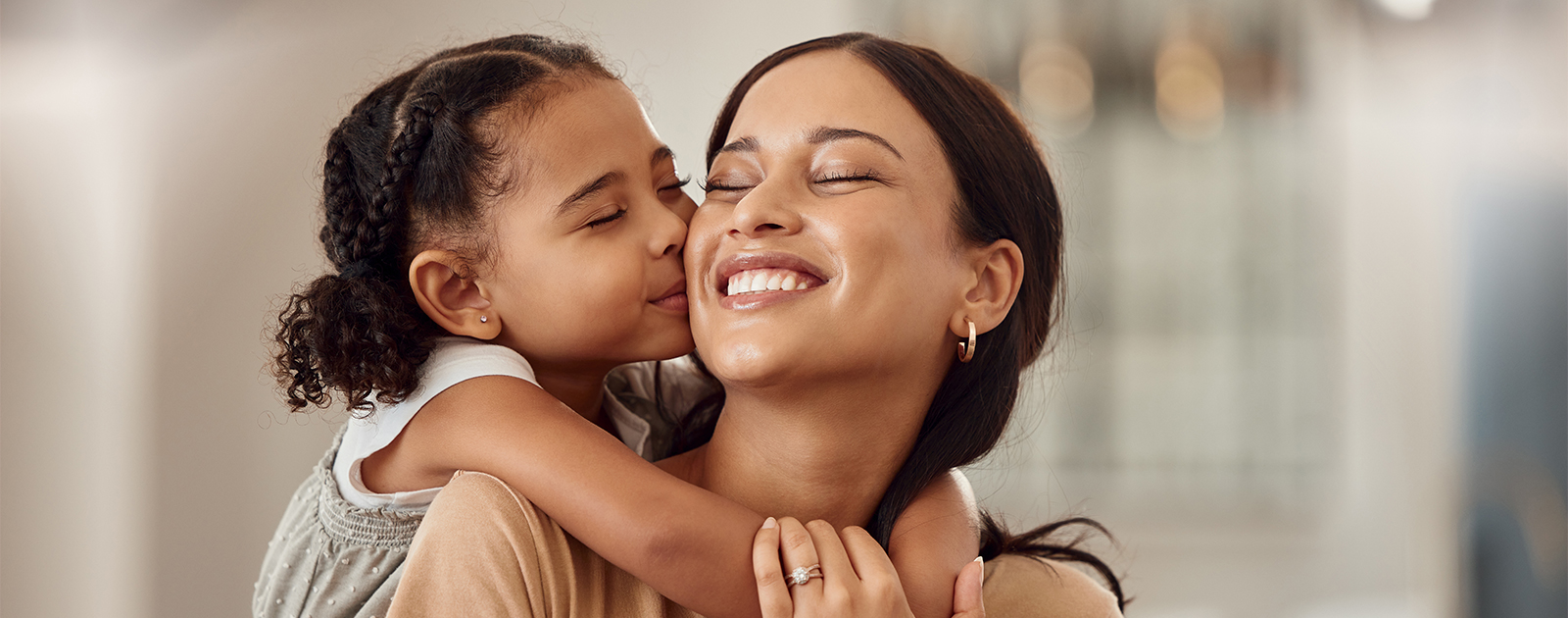 Toddler and young adult woman hug and smile with their eyes closed.