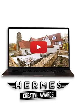A still from the video of the charming Hummingbird Chateau in Unity Village on a black laptop with the Hermes Creative Awards logo