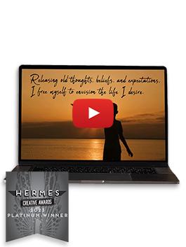 A still from "Live Your Dreams" - A little boy at sunset with the text "Releasing old thought, beliefs, and expectations, I free myself to envision the life I desire" - on a black laptop with a Platinum 2023 Hermes Award