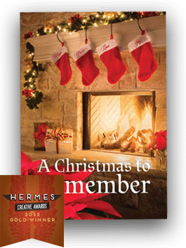 A fire going in the fireplace with four red stockings and Christmas decorations and the text "A Christmas to Remember" with a Gold 2022 Hermes Award